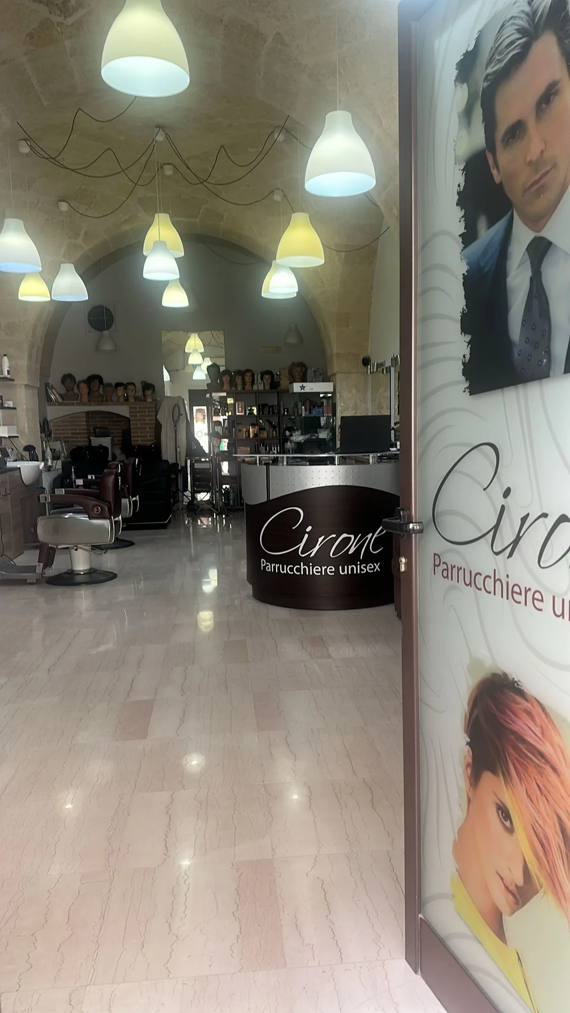 Interno del salone Parrucchiere Cirone, Via Roma 16, 70022 Altamura (BA): la volta in pietra con le lampade sospese, le poltrone da taglio e il banco d'accoglienza