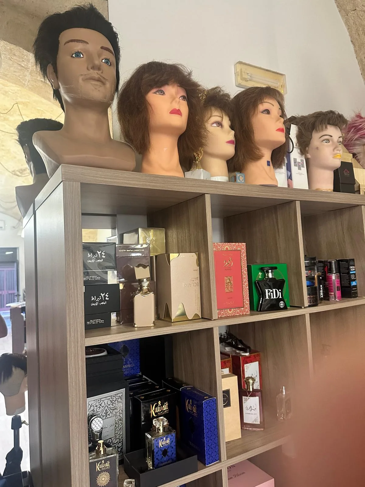 Scaffale del salone Cirone con altre teste da lavoro con capelli e, sotto, i ripiani dei profumi